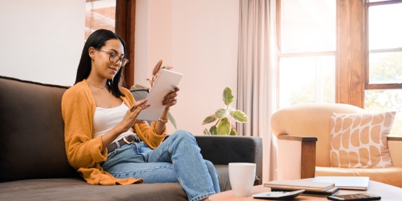 Frau sitzt mit Tablet auf der Couch