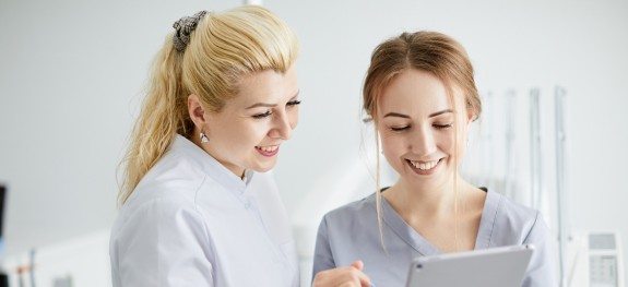 Zahnärztin und ZFA schauen auf ein Tablet
