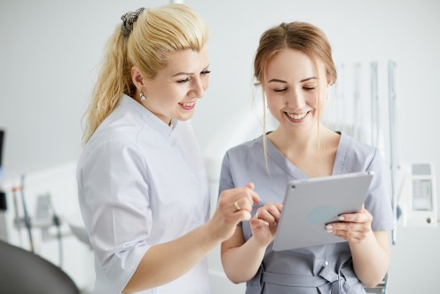 Zahnärztin und ZFA schauen auf ein Tablet 